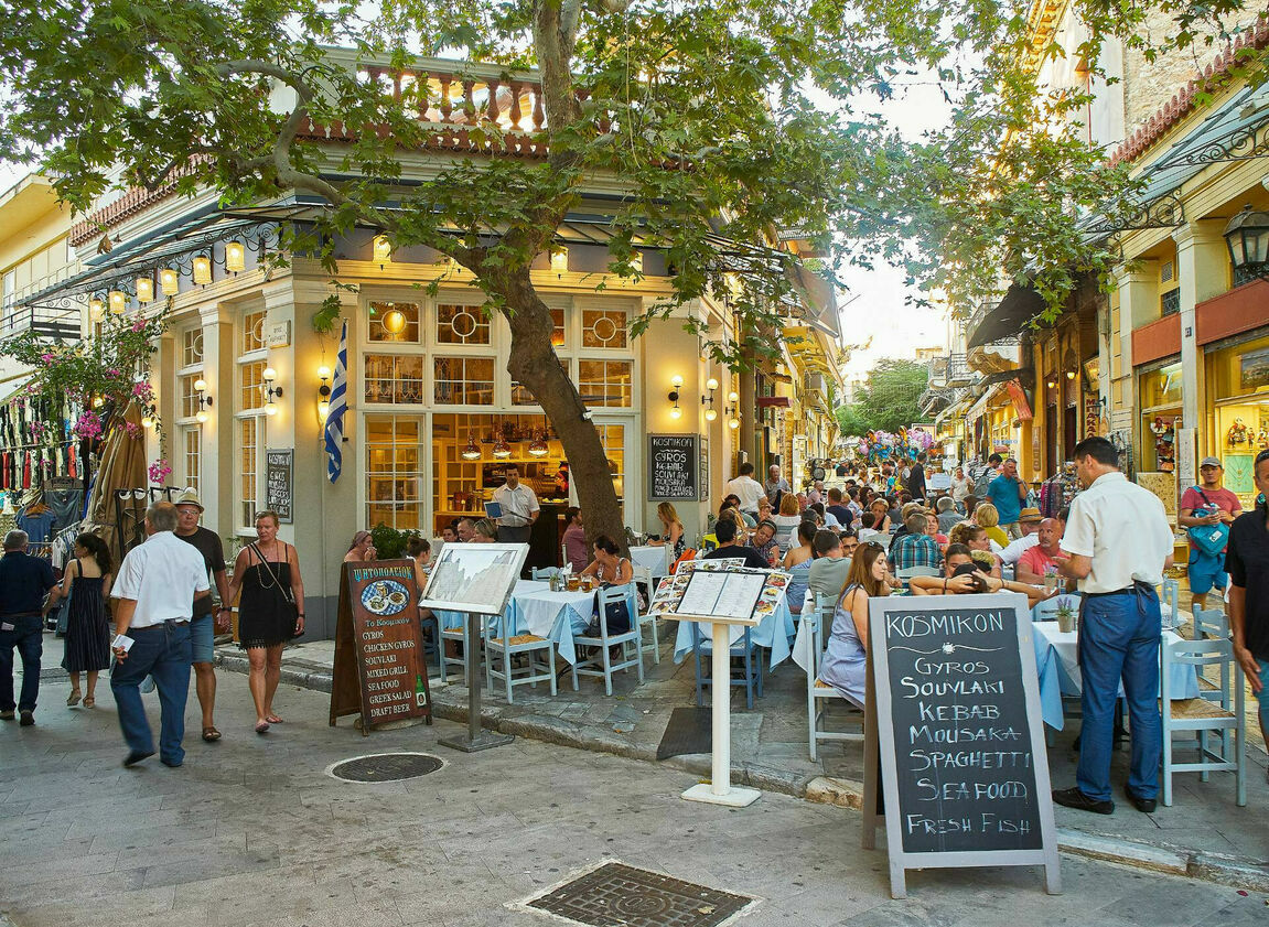 Tourists seated at restaurant, ready to explore the street food in Athens city centre.