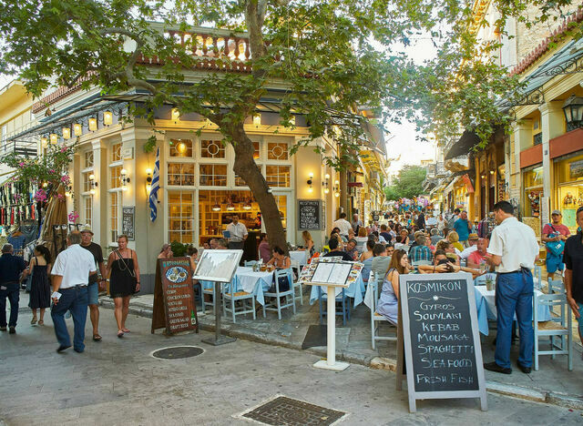 Tourists seated at restaurant, ready to explore the street food in Athens city centre.